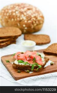 Smoked salmon sandwich with cheese, pistachio and salad leaves, brown breads