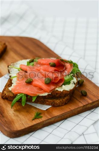 Smoked salmon sandwich with cheese, pistachio and salad leaves, brown breads