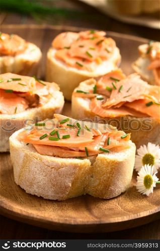 Smoked salmon sandwiches with chives, photographed with natural light (Selective Focus, Focus on the front of the salmon on the first bread)