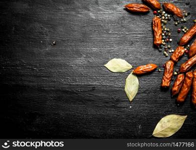 Smoked sausage with spices. On a black wooden background.. Smoked sausage with spices. On black wooden background.