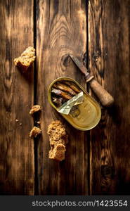 Smoked sprats with rye bread. On wooden background.. Smoked sprats with rye bread.