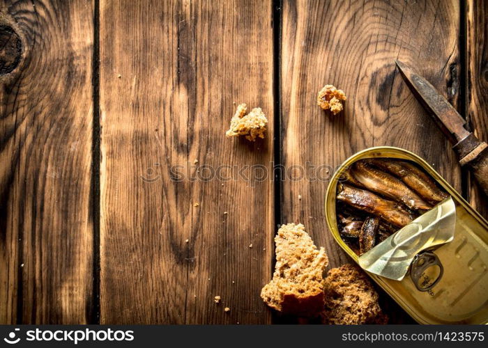 Smoked sprats with rye bread. On wooden background.. Smoked sprats with rye bread.