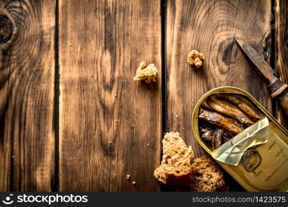 Smoked sprats with rye bread. On wooden background.. Smoked sprats with rye bread.