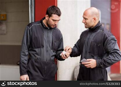 smoking, car service and people concept - auto mechanics with pack of cigarettes at smoko outdoor. auto mechanics with cigarettes at smoking brake