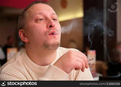 smoking man releases smoke from mouth