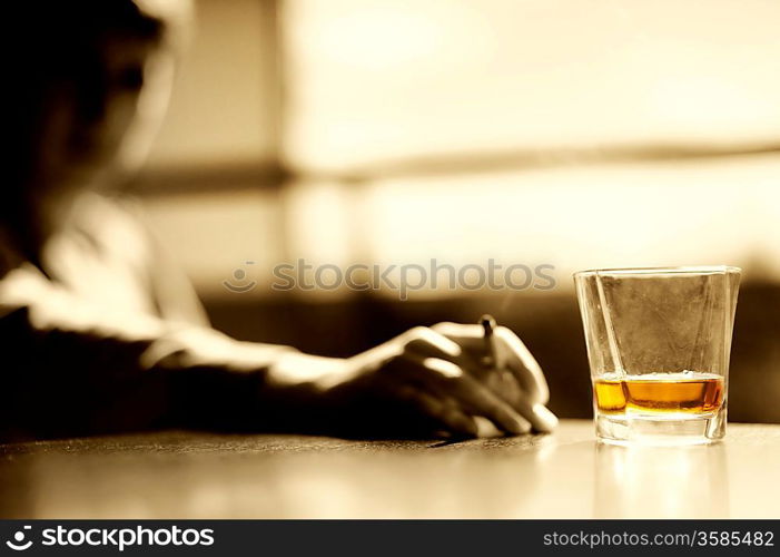 Smoking man with a glass of whisky and cigar