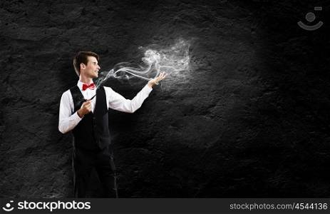 Smoking pipe. Young handsome businessman smoking pipe against black background