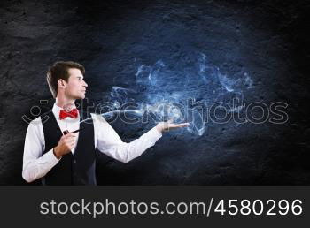 Smoking pipe. Young handsome businessman smoking pipe against black background