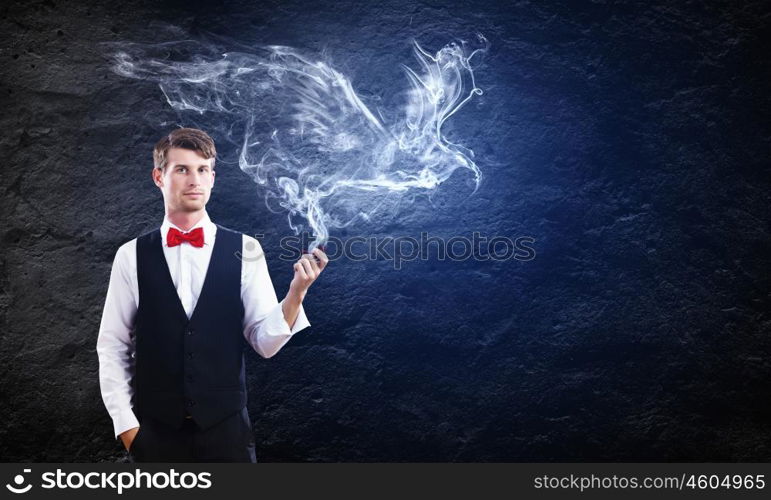 Smoking pipe. Young handsome businessman smoking pipe against black background