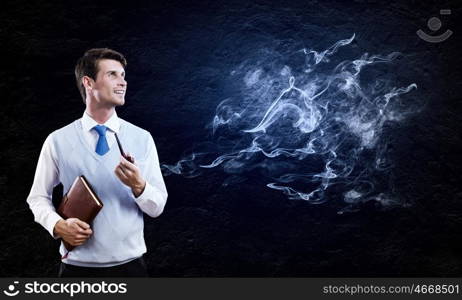 Smoking pipe. Young handsome businessman smoking pipe against black background