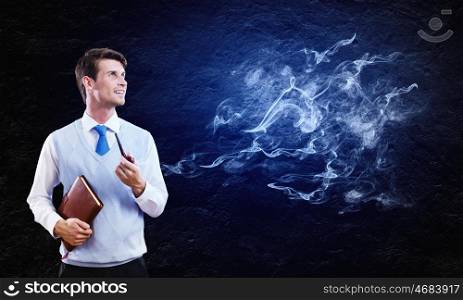 Smoking pipe. Young handsome businessman smoking pipe against black background