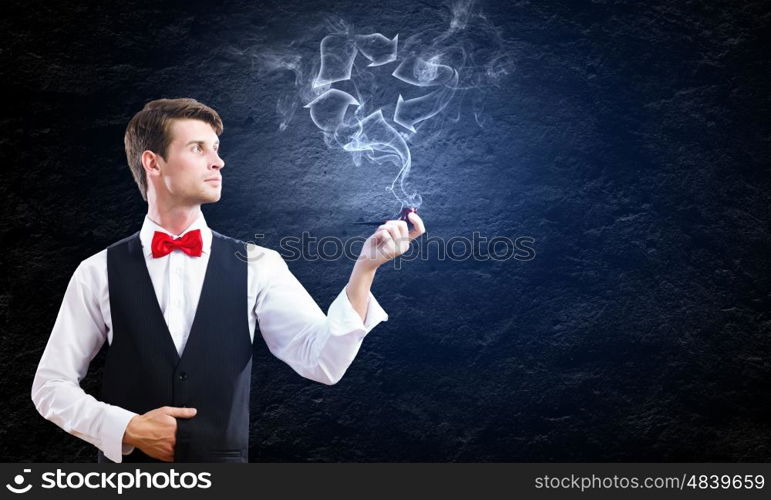 Smoking pipe. Young handsome businessman smoking pipe against black background