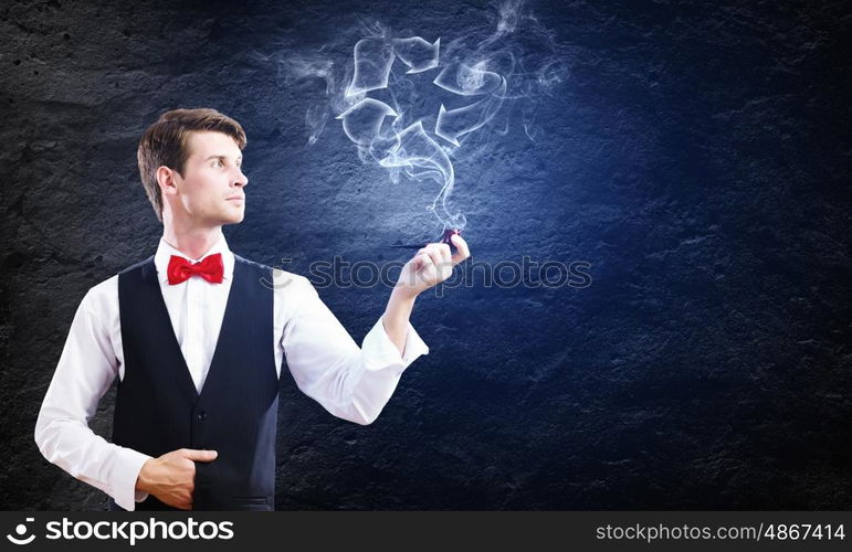 Smoking pipe. Young handsome businessman smoking pipe against black background