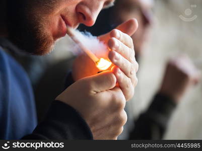 smoking, substance abuse, addiction and bad habits concept - close up of young people lighting cigarette outdoors