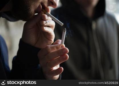 smoking, substance abuse, addiction and bad habits concept - close up of young people lighting cigarette outdoors