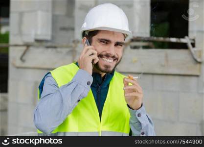 smoking worker using smart phone with factory