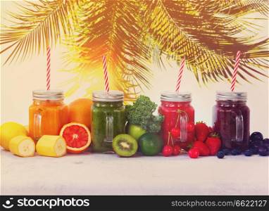Smoothy drinks in glass jars with ingredients on white table under plam tree, retro toned. Fresh smoothy drink