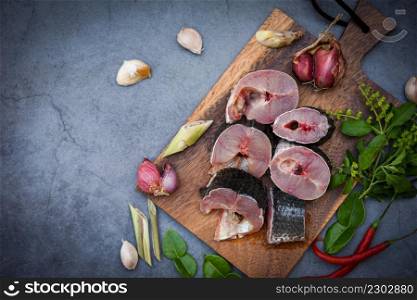 Snakehead fish for cooking food, striped snakehead fish chopped with ingredients herb and spices on wooden cutting board and table kitchen background, Fresh raw Snake head fish menu freshwater fish