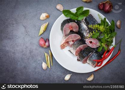 Snakehead fish for cooking food, striped snakehead fish chopped with ingredients herb and spices on white plate and table kitchen background, Fresh raw Snake head fish menu freshwater fish
