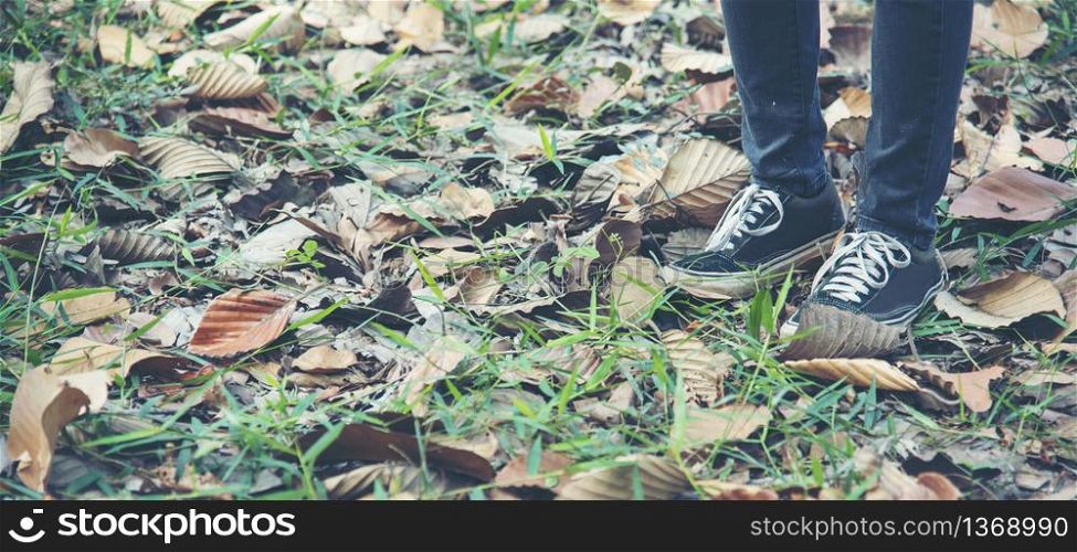 sneaker shoes young woman traveler sit down on summer park. Focus on sneaker shoes and jeans on pathway in forest park. active activity vacation on hike mountain walking way. Young traveler concept