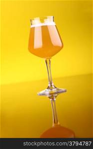 Snifter glass with wheat beer over a bright yellow background