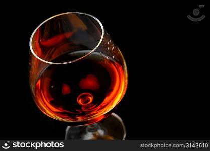 snifter of brandy in elegant glass. black background