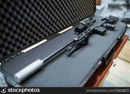Sniper rifle with optical sight in case closeup, gun shop, nobody. Euqipment for hunters on stand in weapon store, hunting and sport shooting hobby. Sniper rifle with optical sight in case, gun shop