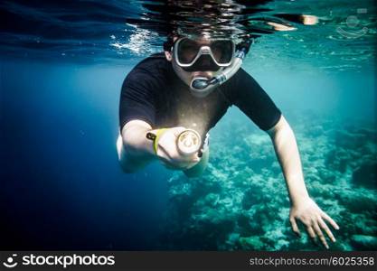 Snorkeler diving along the brain coral with flashlight