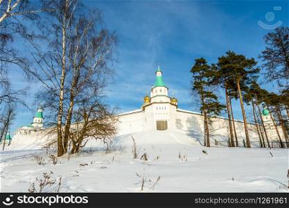 Snow and white walls, golden domes and a tower gate of New Jerusalem Monastery, Istra, Moscow region, Russia
