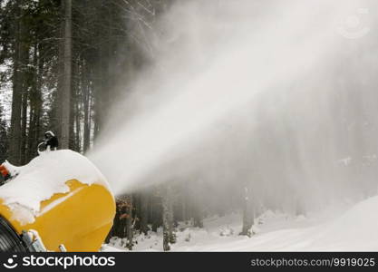 Snow cannon during snowmaking slope in winter. Machine produce snow at ski resort. 