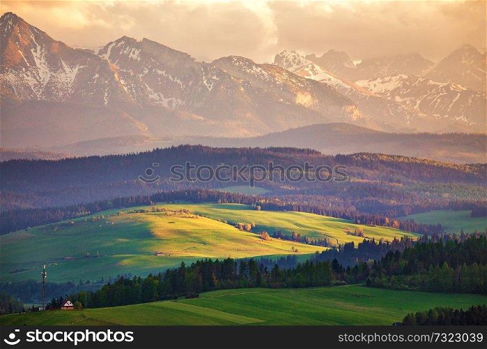 Snow caped mountains and green fields and meadows in Malopolska region, Poland. Spring sunset in Tatra Mountains, Pieniny range