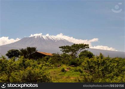 Snow capped Kenya’s Kilimanjaro mountain under cloudy blue sky captured on Kenya Africa safari.