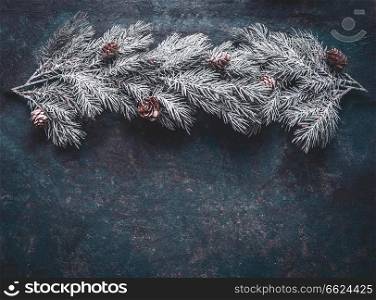 Snow covered fir branches with cones on dark blue background, top view with copy space for your design. Winter and Christmas concept