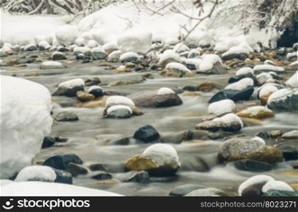 Snow-covered mountain river shot with long exposure