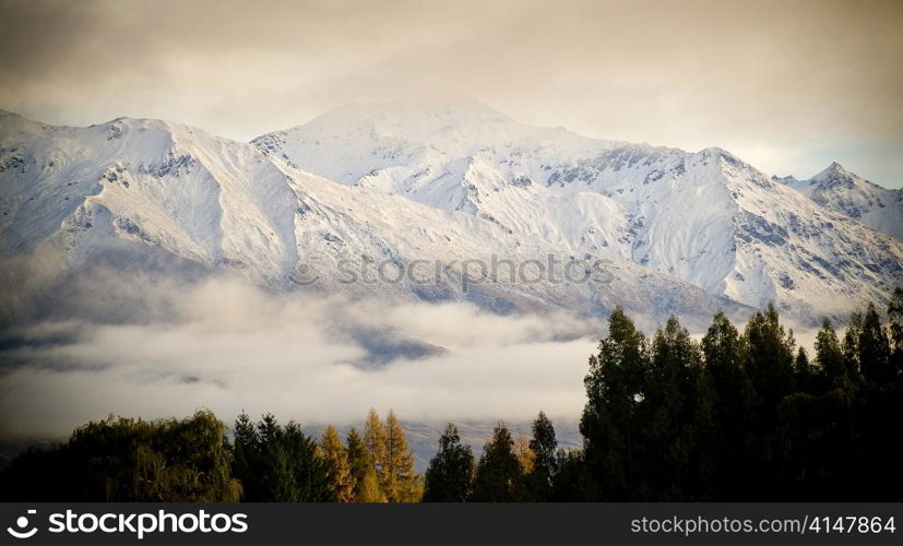 Snow covered peaks wrapped in cloud at sunrise