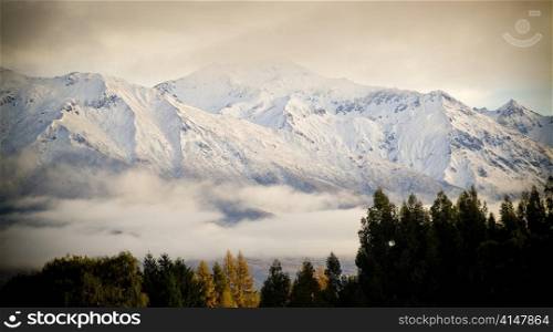 Snow covered peaks wrapped in cloud at sunrise