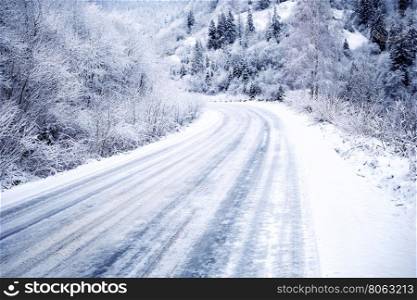 Snow-covered road in forest between mountains. Snow-covered road in forest