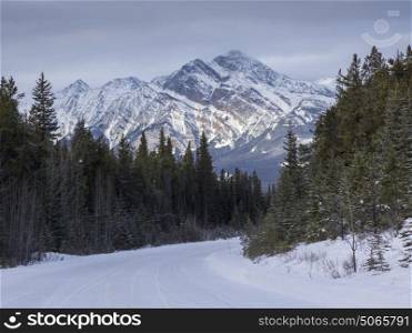 Snow covered road leading toward mountain range, Maligne Lake, Highway 16, Yellowhead Highway, Jasper, Jasper National Park, Alberta, Canada