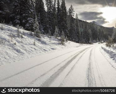 Snow covered road leading toward mountain range, Maligne Lake, Jasper, Jasper National Park, Alberta, Canada