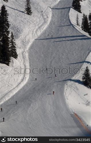 Snow covered ski piste surrounded by trees on sunny day at Montafon, Austria