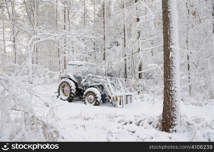 Snow covered tractor in woodland