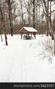 snow covered wooden pavilion in urban park in winter