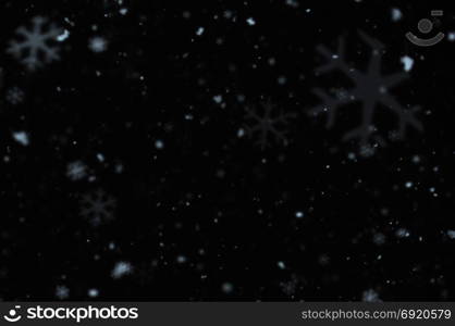 Snow falling on cold winter night. Snowflakes bokeh blur effect abstract background.