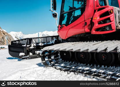 Snow grooming machine (Ratrak). Winter mountain landscape. Caucasus ridge covered with snow in sunny day. Krasnaya Polyana, Sochi, Russia