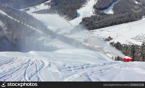 snow gun shoots at snowy mountains in winter