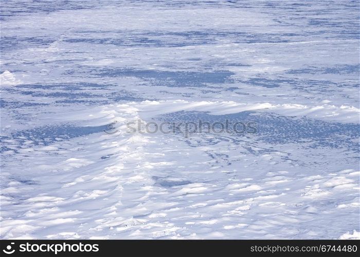 Snow hummocks on the surface of frozen pond