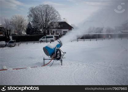 Snow making machine working on ski slope at cold cloudy day