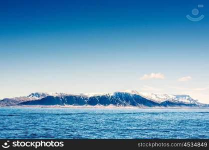 Snow on mountains in the blue ocean in Iceland
