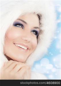 Snow queen, beautiful woman in Christmas style makeup, female portrait over blue holiday background with shiny glowing glitters and bokeh lights