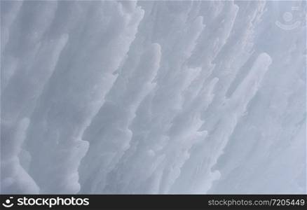 Snow texture with waves of frozen snow. Wall of snow close-up.